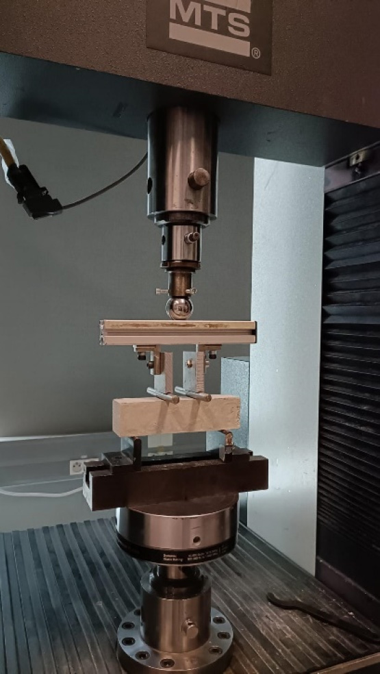 A photograph of completed four-point bending tests at the Navier laboratory features a setup related to materials testing, specifically focusing on four-point bending tests being conducted in an indoor laboratory environment. It is associated with M T S. 