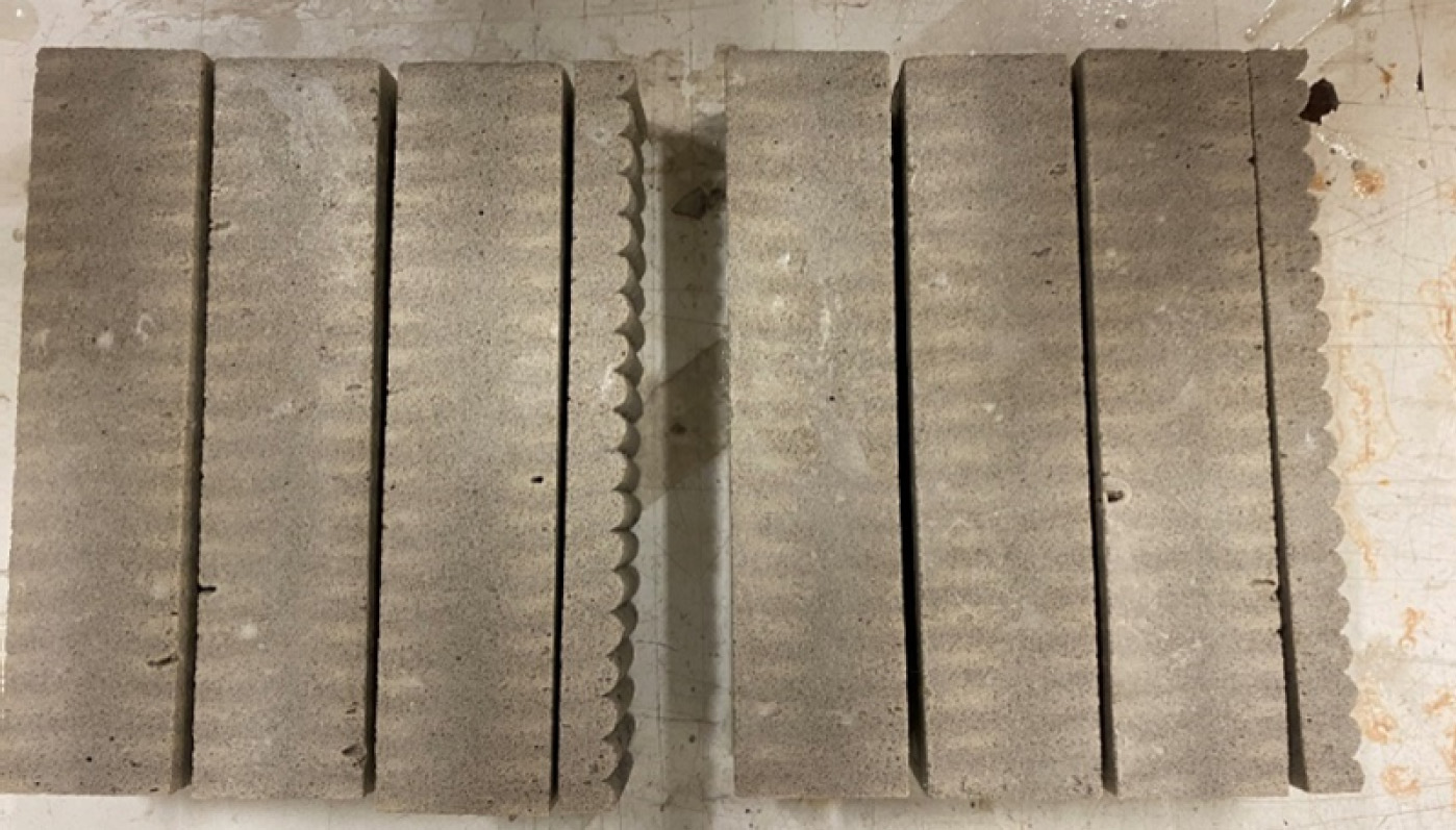 A photograph close-up view of wood, capturing its texture and details. It is associated with the process of cutting prismatic specimens from a printed piece, showing traces related to various materials and systems used. The relevant tags include rectangle, parallel, wood, text, and line.