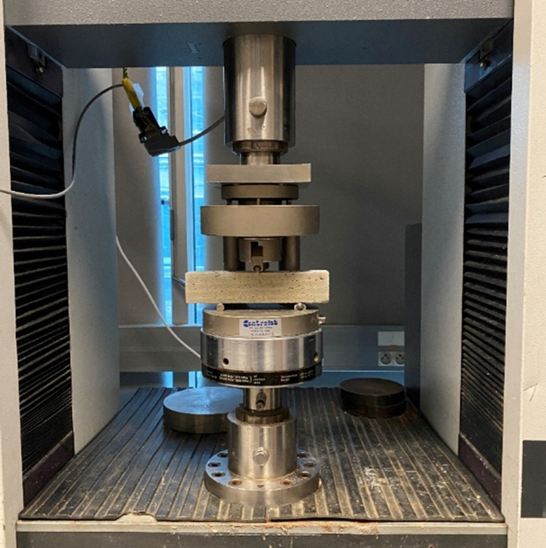 An image features a machine with a long tube, which is part of the three-point bending tests conducted at the Navier laboratory. It falls under the category of machines and appliances, specifically relating to small kitchen appliances.